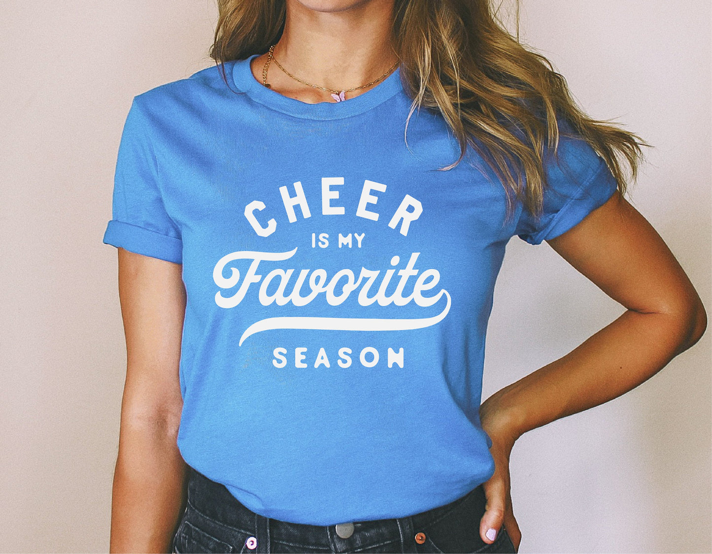 Woman wearing blue t-shirt with 'Cheer is My Favorite Season' slogan, perfect for cheerleading fans and enthusiasts.