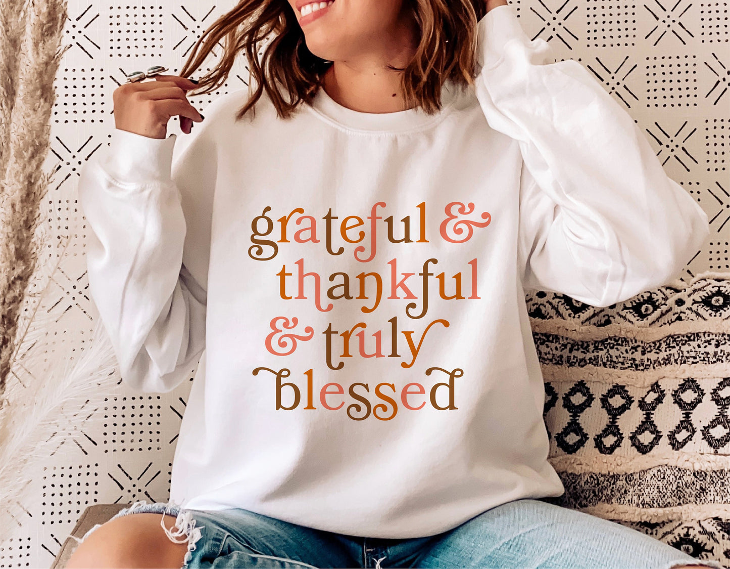 Woman wearing a white sweatshirt with 'Grateful & Thankful & Truly Blessed' text, perfect for Thanksgiving and fall fashion.