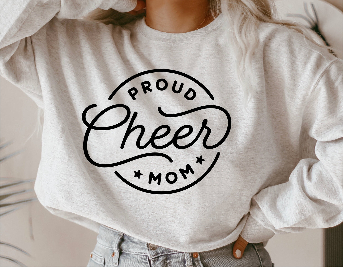 Woman wearing a sweater with 'Proud Cheer Mom' design, showcasing cheerleader support. Ideal for SVG, cut files, sublimation projects.