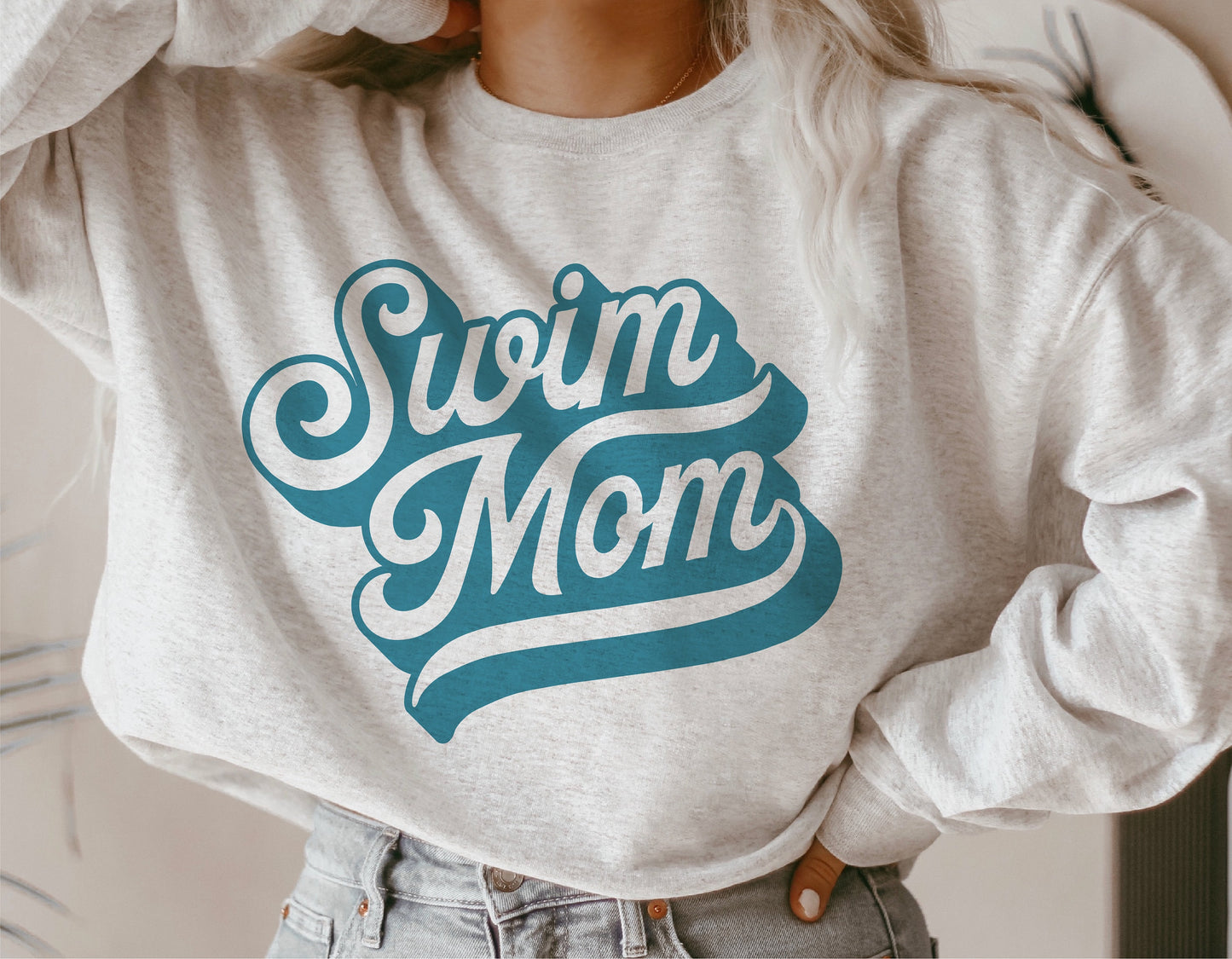 Person wearing a sweatshirt with "Swim Mom" design, ideal for shirts, decals, and sublimation projects, featuring blue and white text.