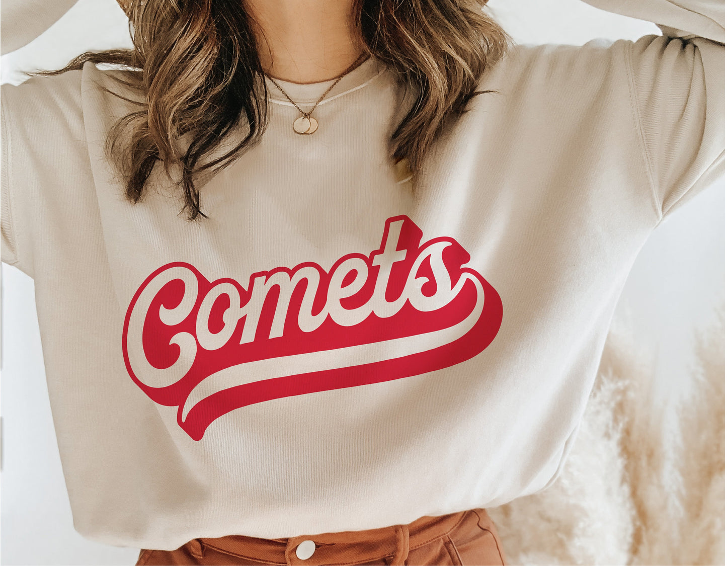 Woman wearing beige shirt with red 'Comets' script text, showcasing team spirit and vintage sports style design.