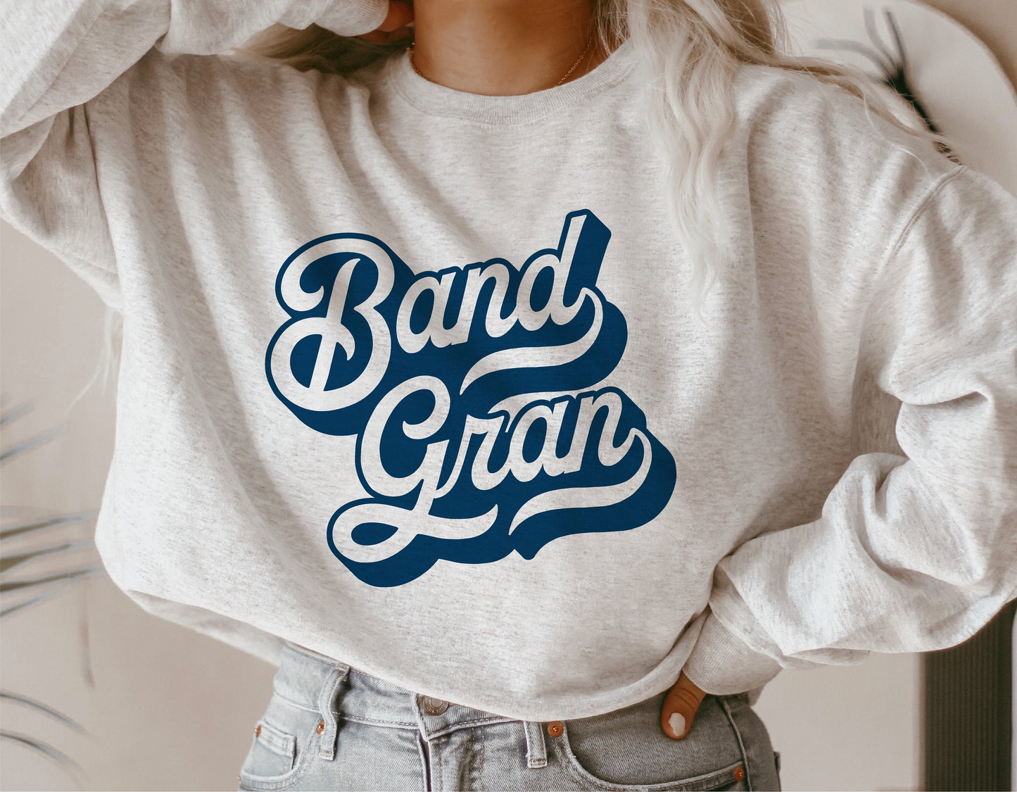 Woman wearing a gray sweatshirt with 'Band Gran' text, perfect for marching band grandmas, school spirit, and sports events.