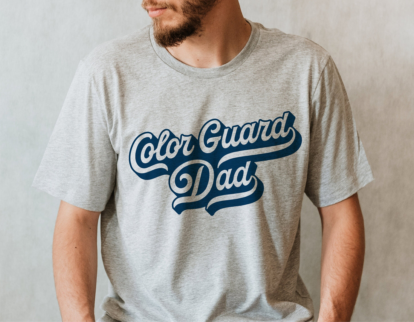 Man wearing a gray t-shirt with 'Color Guard Dad' printed in blue, perfect for marching band enthusiasts and school spirit.
