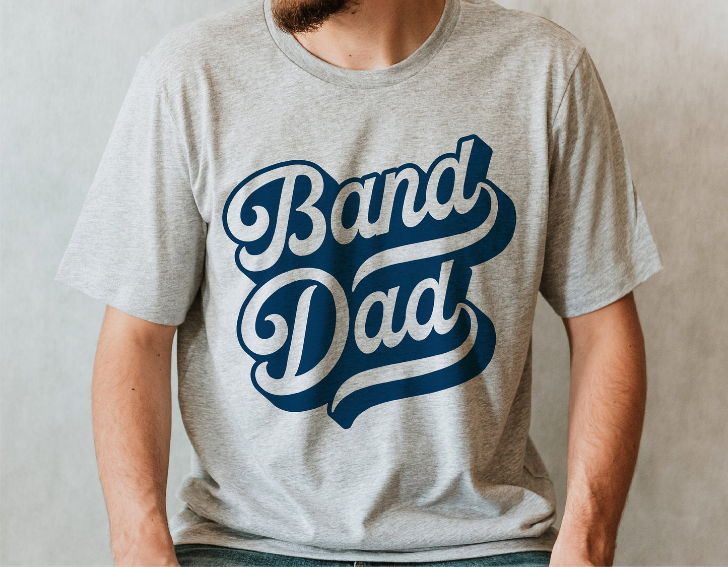 Person wearing a gray t-shirt with 'Band Dad' printed in bold lettering, ideal for marching band enthusiasts and school spirit events.