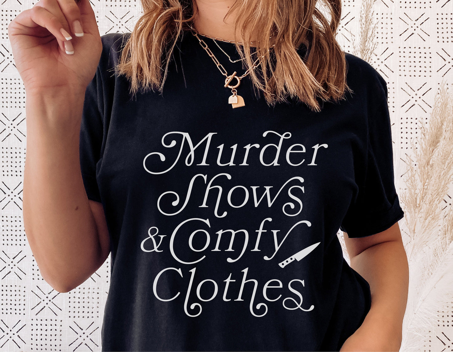 Woman wearing 'Murder Shows & Comfy Clothes' black t-shirt, featuring a playful true crime theme. Ideal for Halloween and sublimation design.