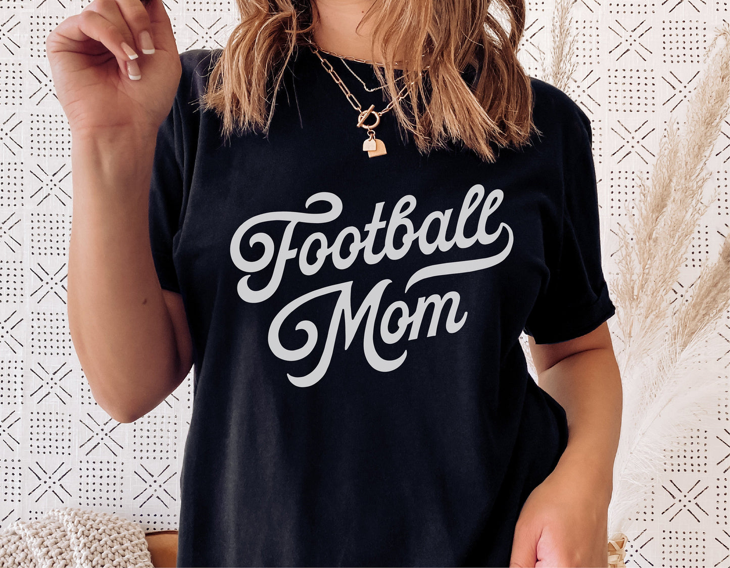 Woman wearing a black Football Mom shirt with vintage script design, ideal for sports fan SVG projects and digital cut files.