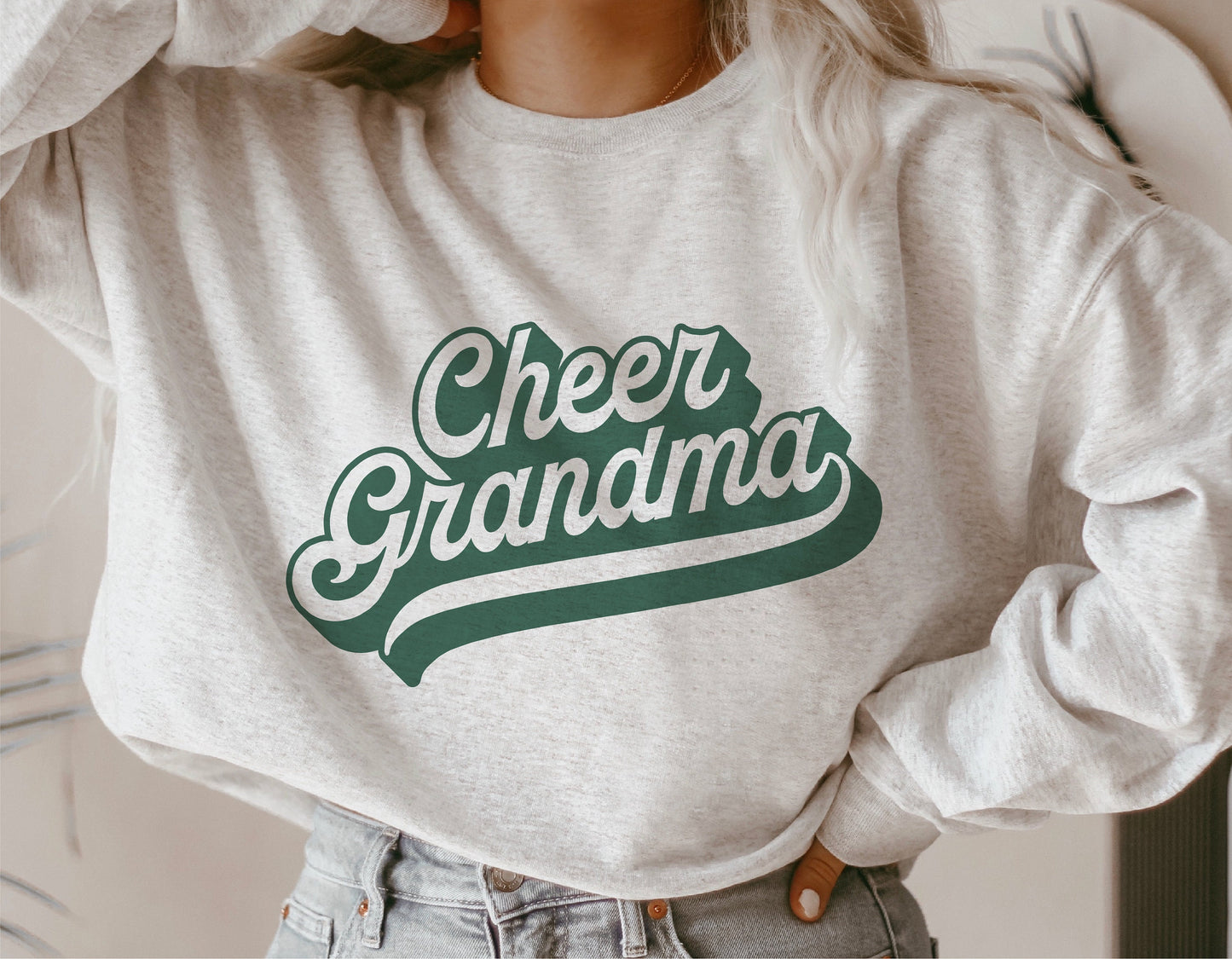 Woman wearing a sweatshirt featuring a 'Cheer Grandma' design in green, showcasing a sporty team spirit style for cheerleading events.