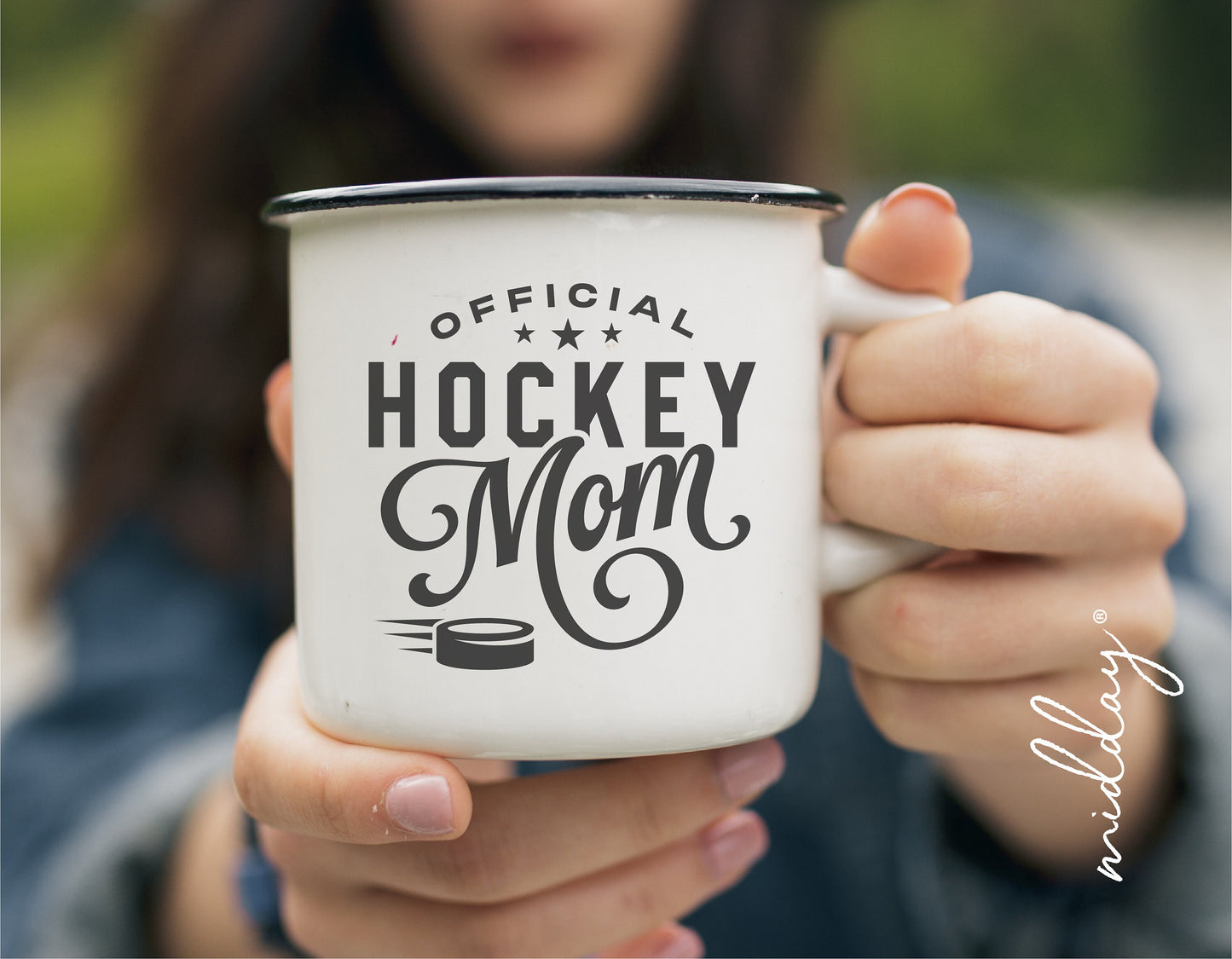 White mug with 'Official Hockey Mom' design in black font, held by a person with blurred background.