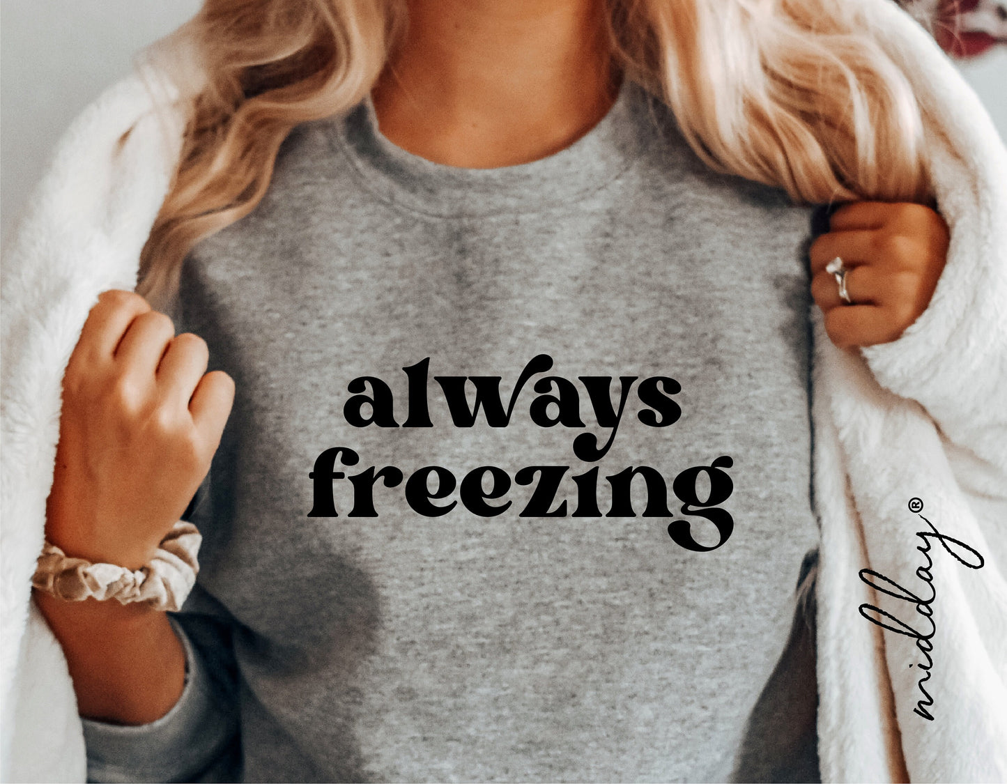 Woman wearing a grey sweatshirt with 'always freezing' text, cozy winter style.