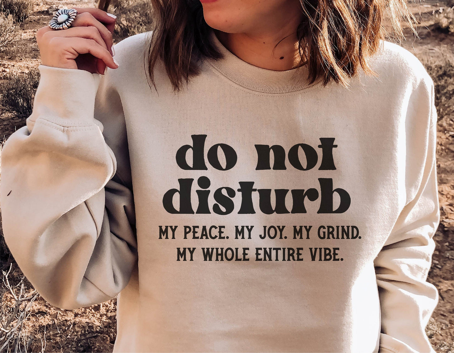 Woman wearing sweatshirt with 'do not disturb' funny quote, outdoor setting