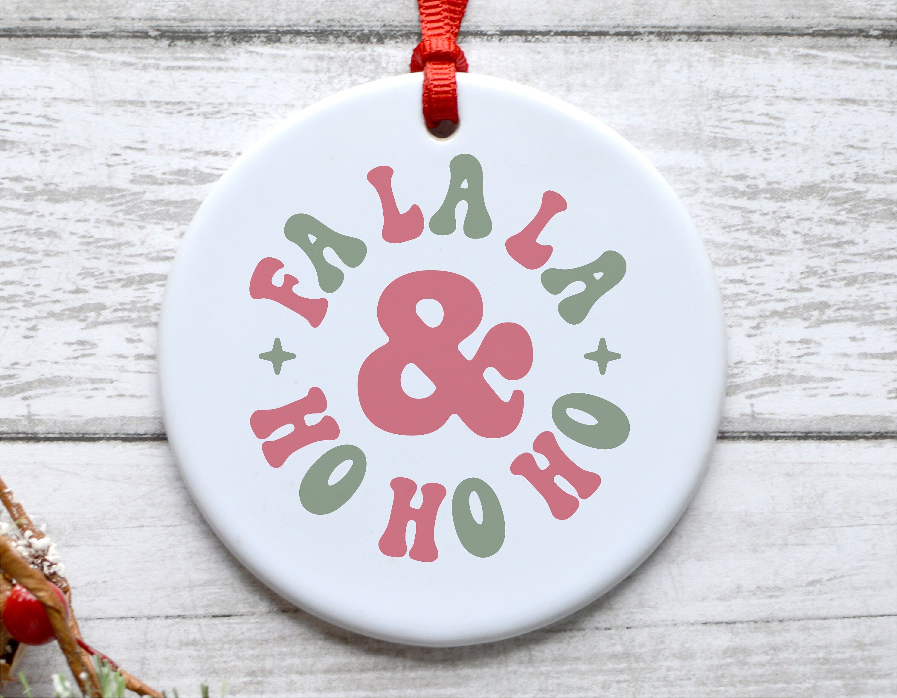 Fa La La Ho Ho Ho Christmas ornament with festive typography and red ribbon on wooden background