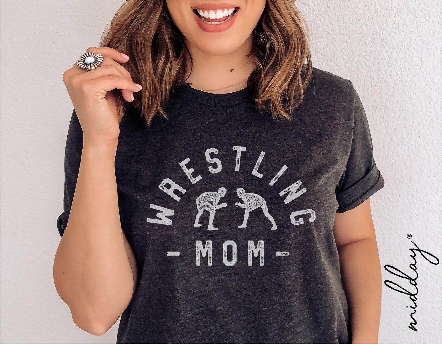 Woman wearing a black 'Wrestling Mom' t-shirt with wrestling figures, showcasing casual sports-themed apparel.