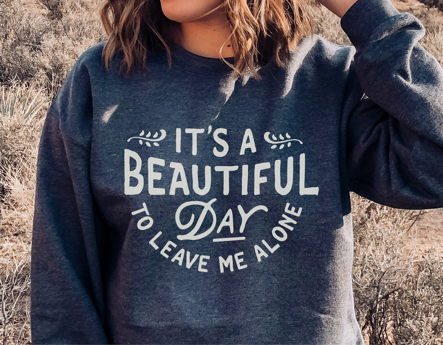 "It's A Beautiful Day To Leave Me Alone" message on a casual sweatshirt outdoors.