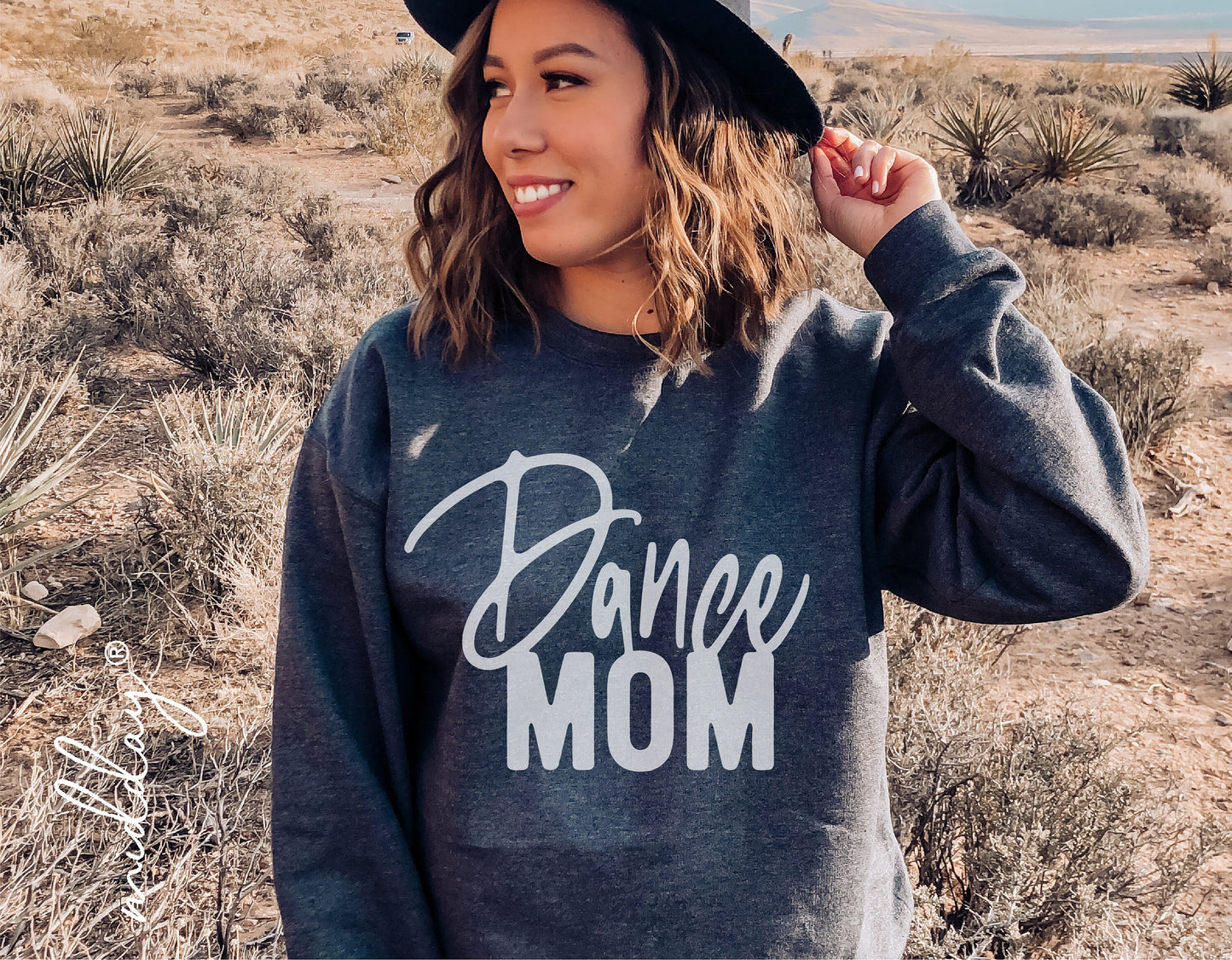 Woman wearing a 'Dance Mom' sweatshirt standing in a desert landscape