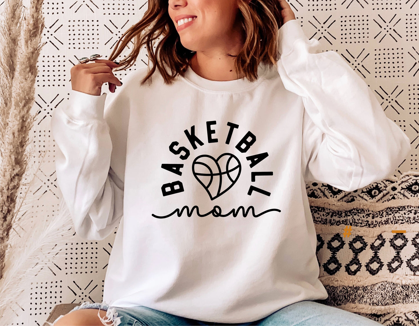 Woman wearing a white sweater with a 'Basketball Mom' design, perfect for sports enthusiasts and digital design projects.
