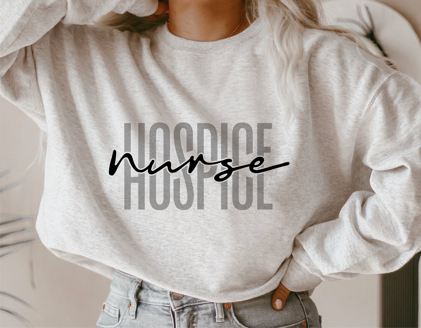Gray sweatshirt with 'Hospice Nurse' stylish text, worn by person with hands on hips.