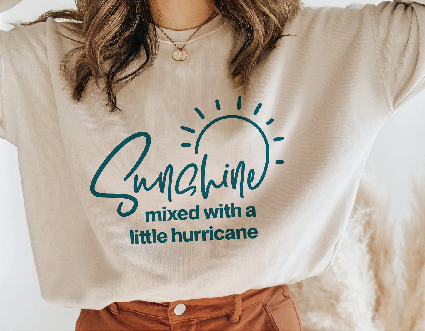 Woman wearing a beige shirt with 'Sunshine mixed with a little hurricane' graphic, perfect for Cricut and sublimation projects.