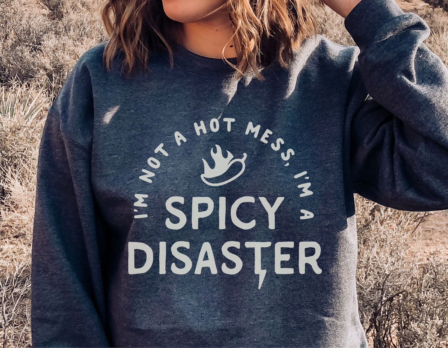 Person wearing a sweatshirt with 'I'm Not A Hot Mess, I'm A Spicy Disaster' print, showcasing sarcastic and sassy fashion style.