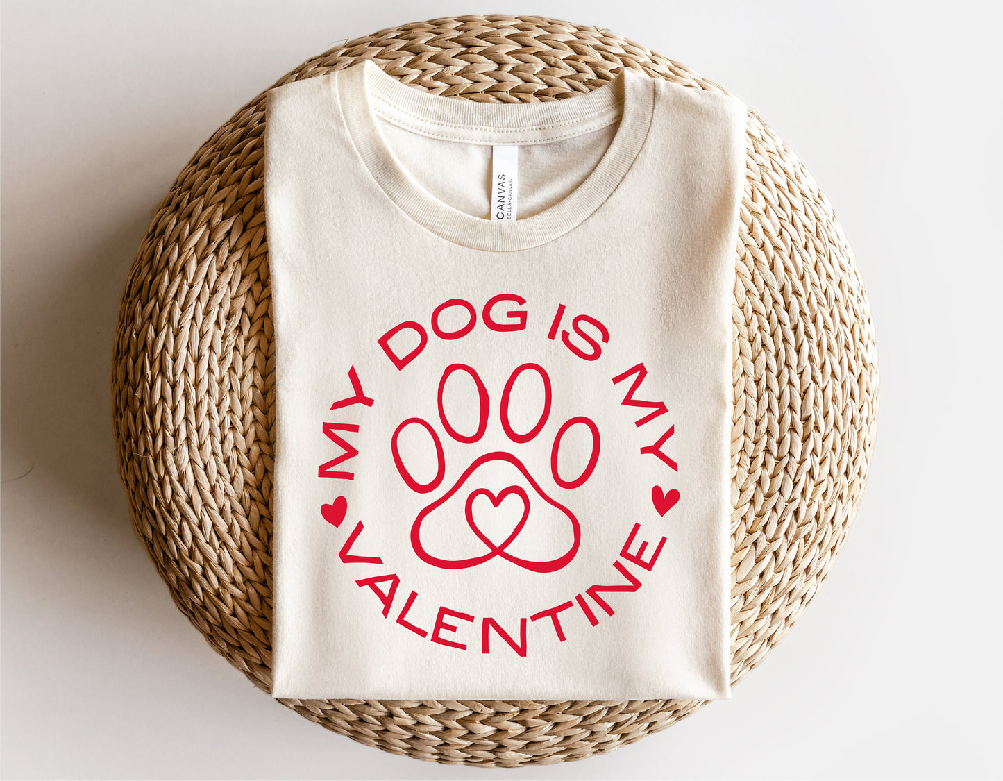 "My Dog Is My Valentine" shirt with red dog paw heart design, perfect for Valentine's Day, displayed on a woven mat.