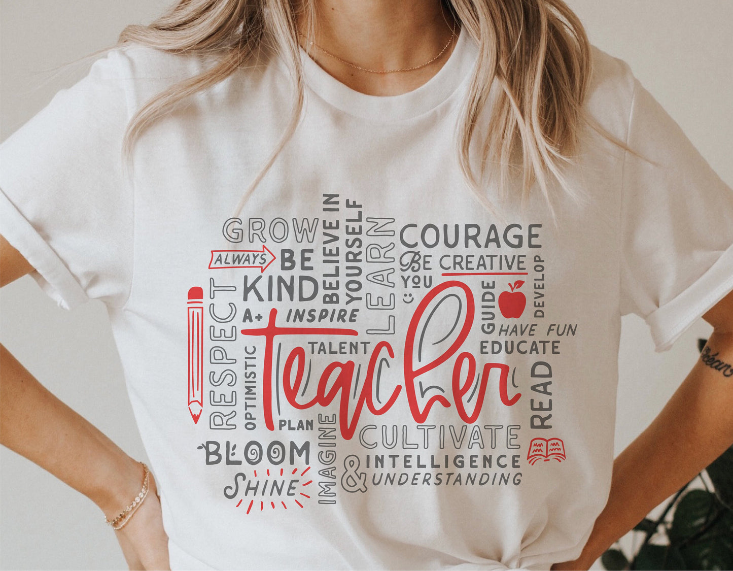 White teacher shirt with motivational word art design featuring words like 'Respect,' 'Inspire,' 'Grow,' and 'Educate.'