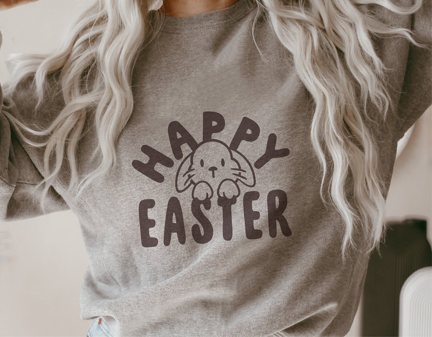 Woman wearing grey sweater with 'Happy Easter' and bunny graphic, ideal for Easter-themed Cricut and Silhouette projects.