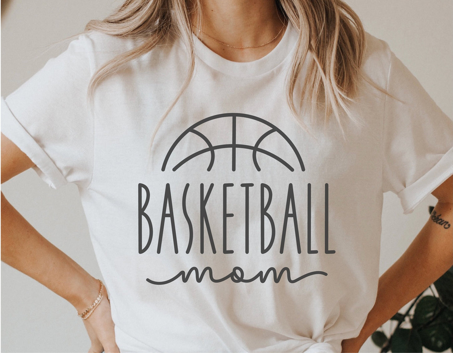 Woman wearing a white t-shirt with a 'Basketball Mom' graphic design, perfect for basketball enthusiasts.