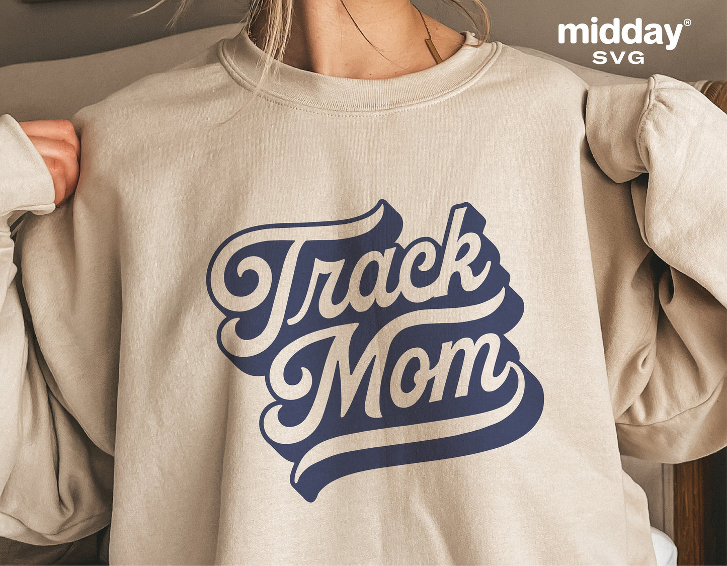 Beige sweatshirt featuring 'Track Mom' design in blue script, ideal for track and field enthusiasts. Available as a digital download.
