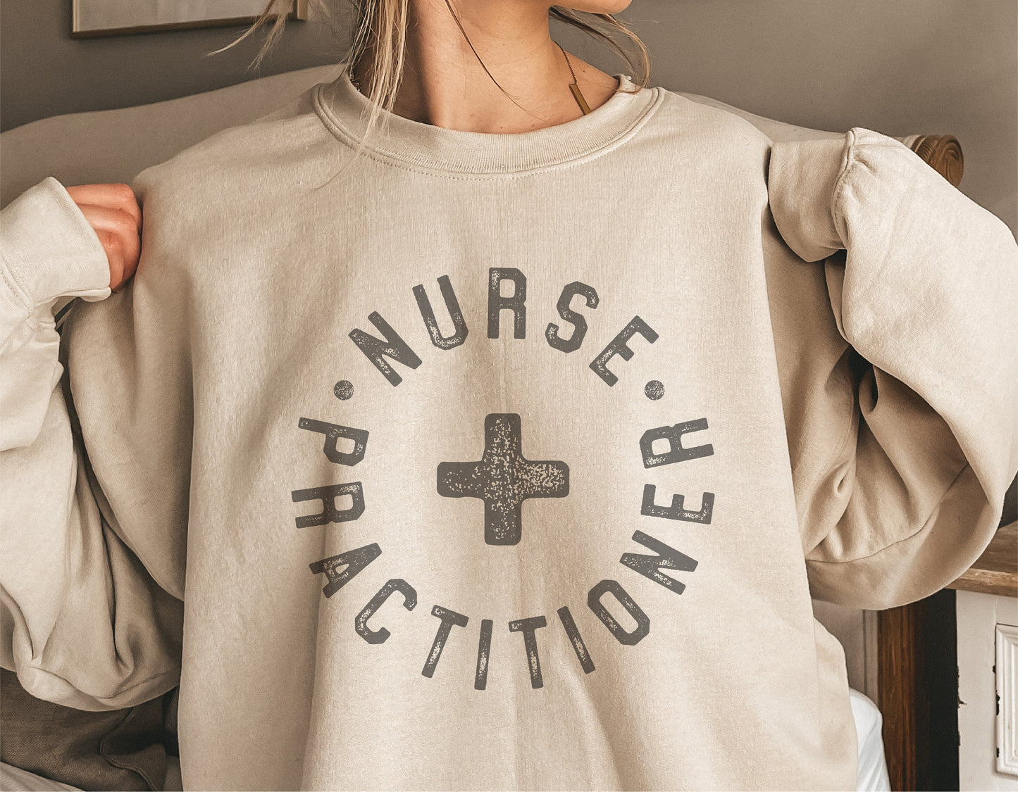 Beige sweatshirt with 'Nurse Practitioner' text and cross graphic, ideal for custom decals and Cricut cut files.