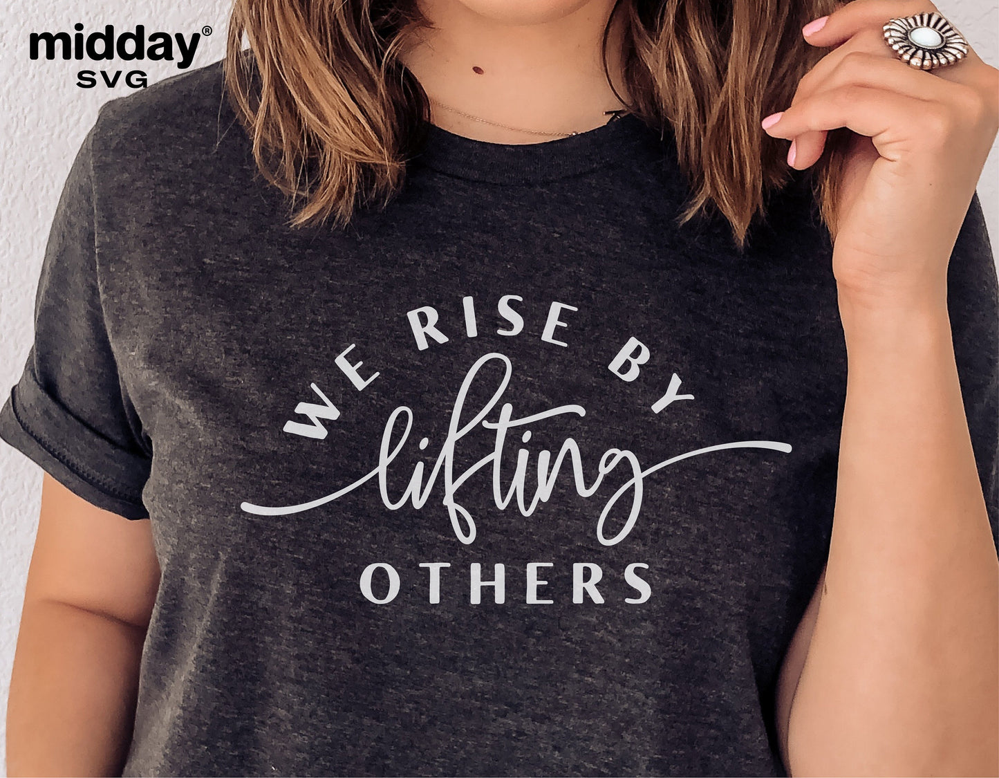 Woman wearing a dark shirt with 'We Rise By Lifting Others' text design, promoting kindness and positivity, ideal for Cricut and Silhouette crafts.