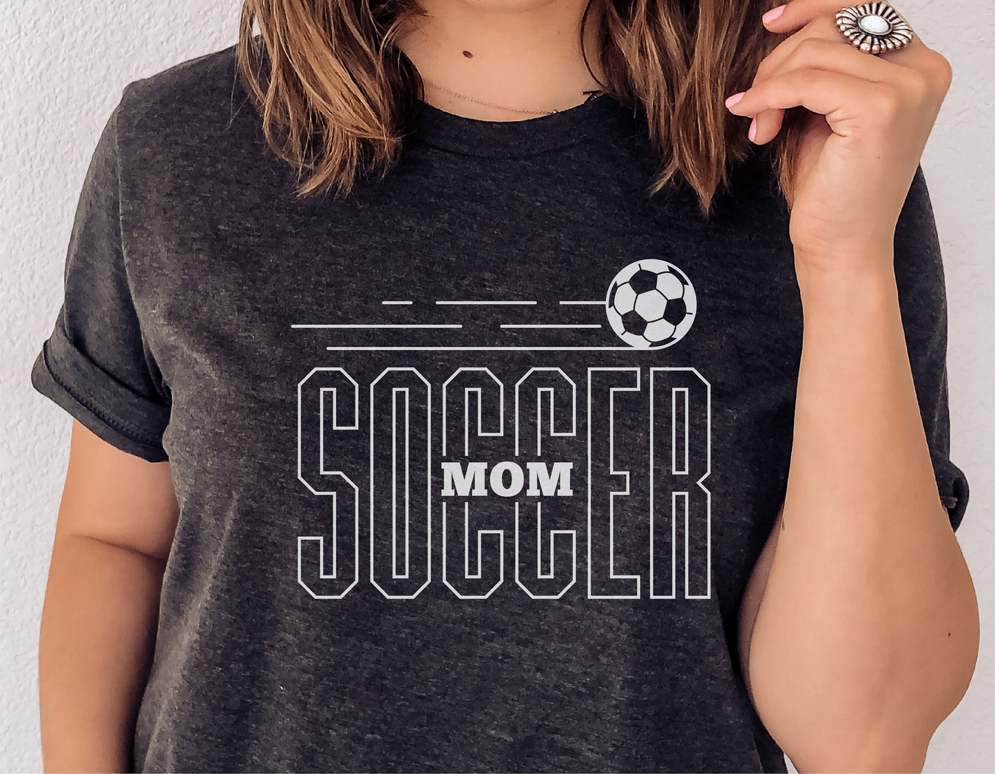 Woman wearing a gray t-shirt with 'Soccer Mom' graphic and soccer ball illustration, perfect for Cricut and Silhouette projects.