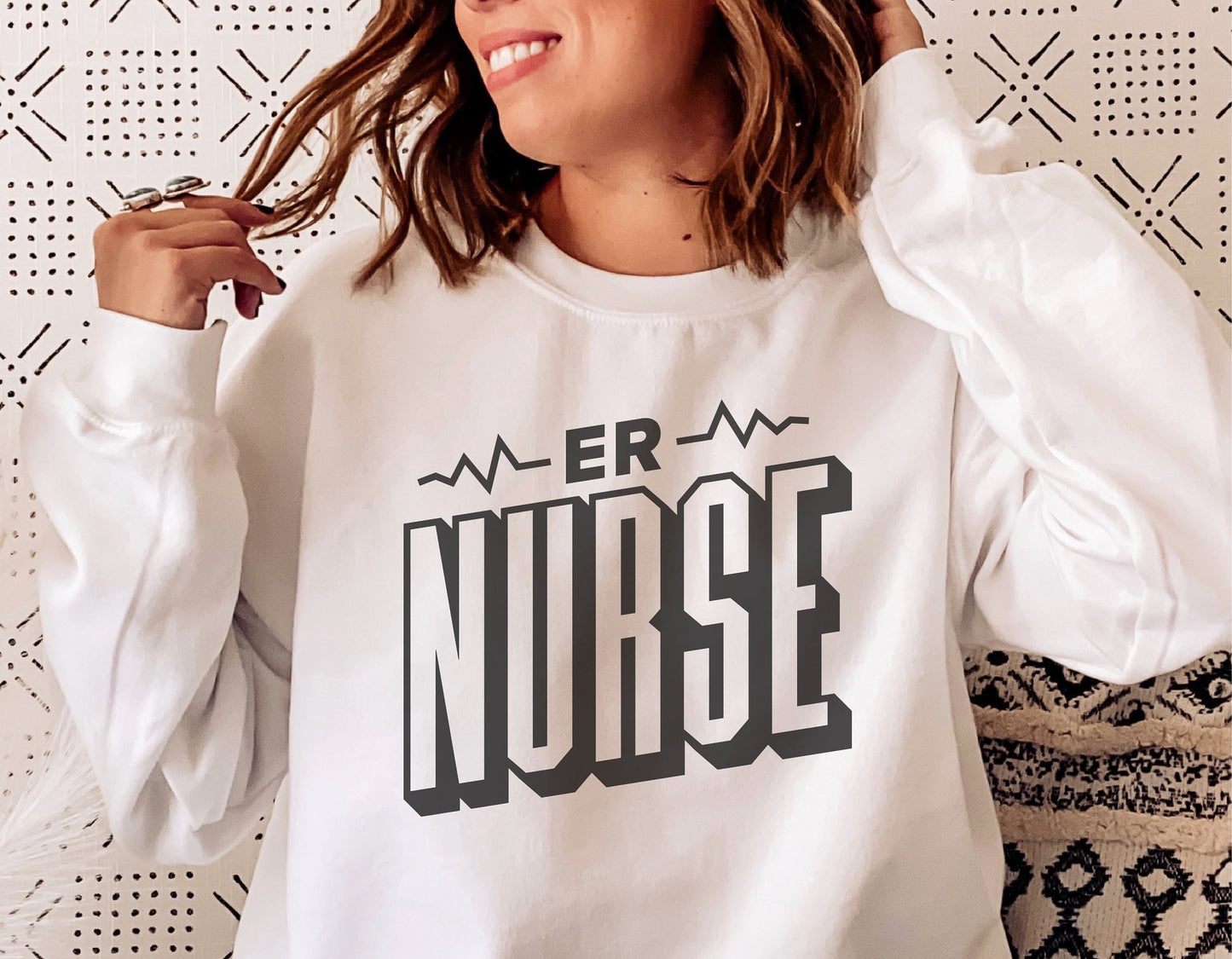 Woman wearing a white sweatshirt with 'ER Nurse' text design, perfect for Cricut and Silhouette projects.