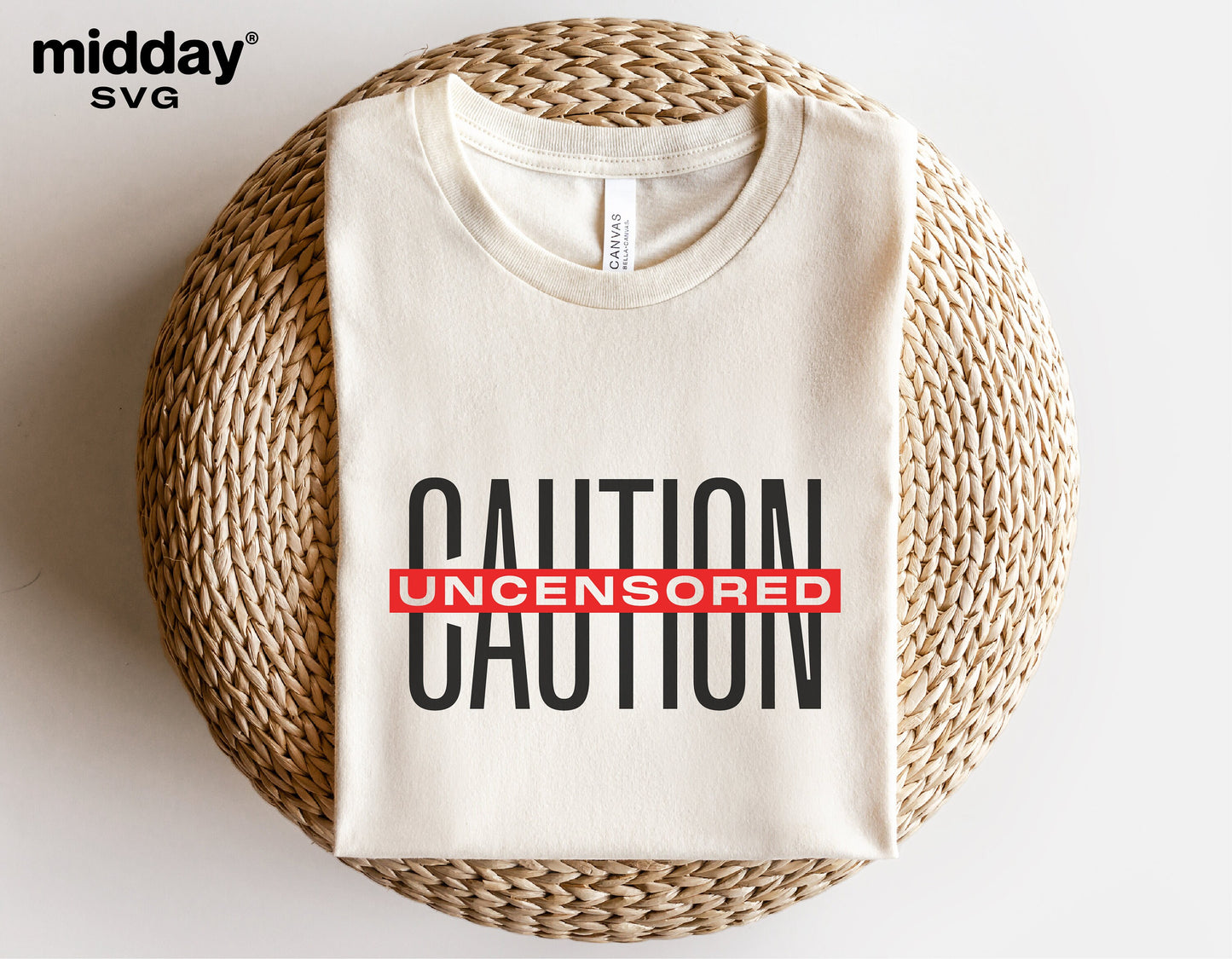 Caution Uncensored t-shirt folded, featuring a bold design, resting on a wicker surface. Ideal for Cricut and Silhouette crafting projects.