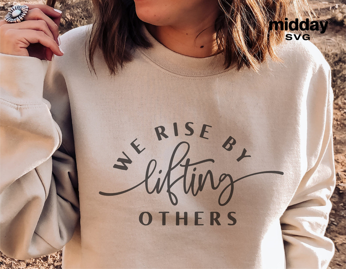 Woman wearing a sweater with 'We Rise By Lifting Others' text design, emphasizing positivity and kindness on apparel.
