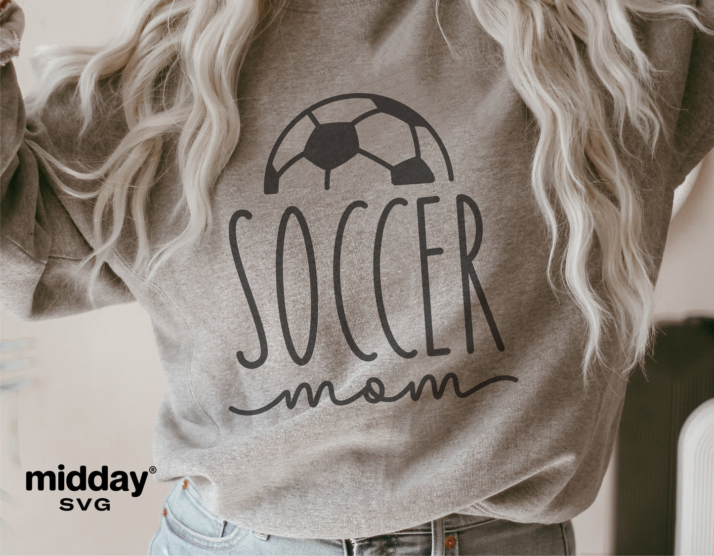 Woman wearing a gray sweatshirt with 'Soccer Mom' and soccer ball graphic design, ideal for Cricut and Silhouette projects.