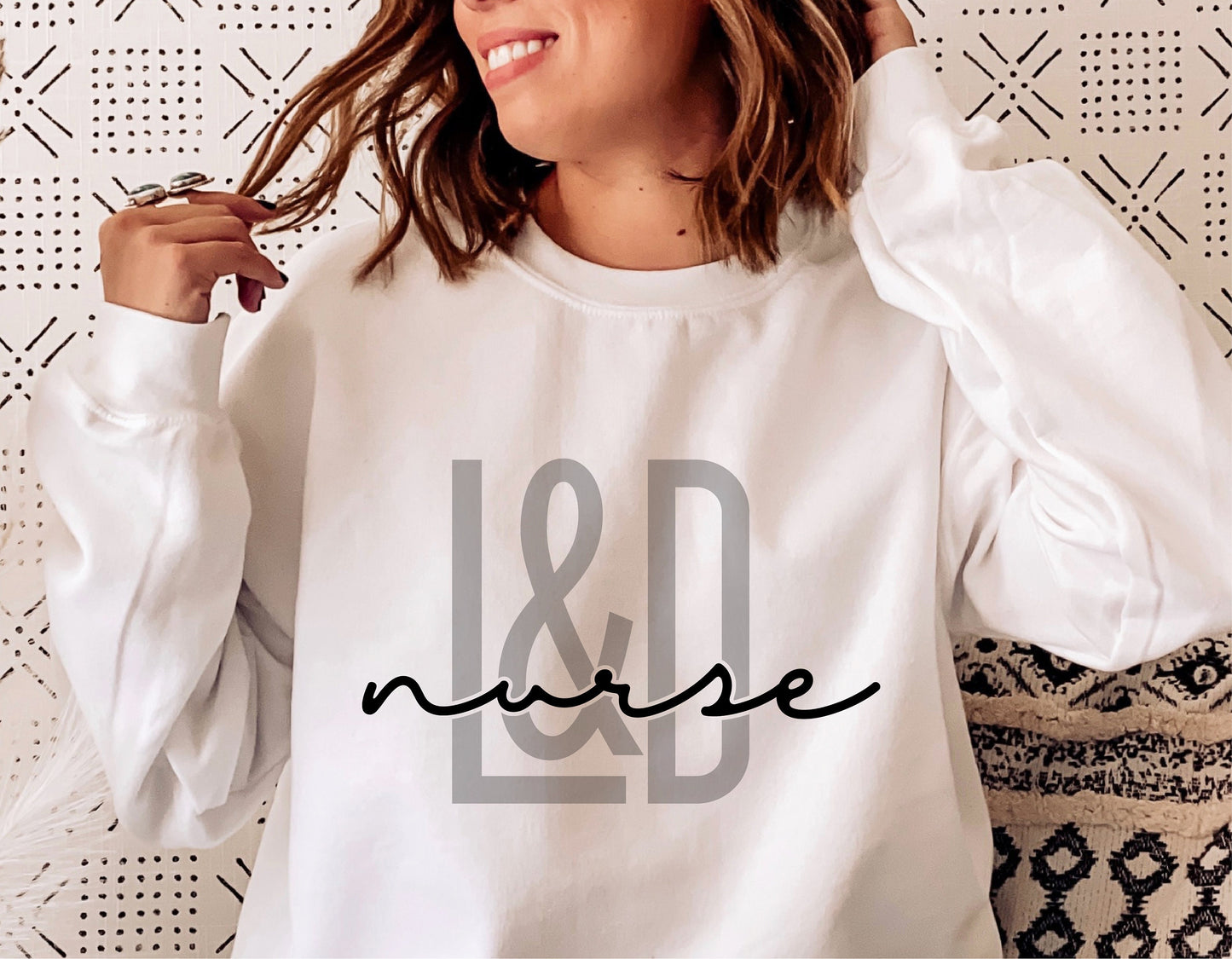 Woman wearing white sweatshirt with 'L&D Nurse' design, ideal for labor and delivery nurse svg craft projects.