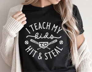 Black t-shirt with 'I Teach My Kids to Hit & Steal' baseball graphic design, worn by woman in cardigan.