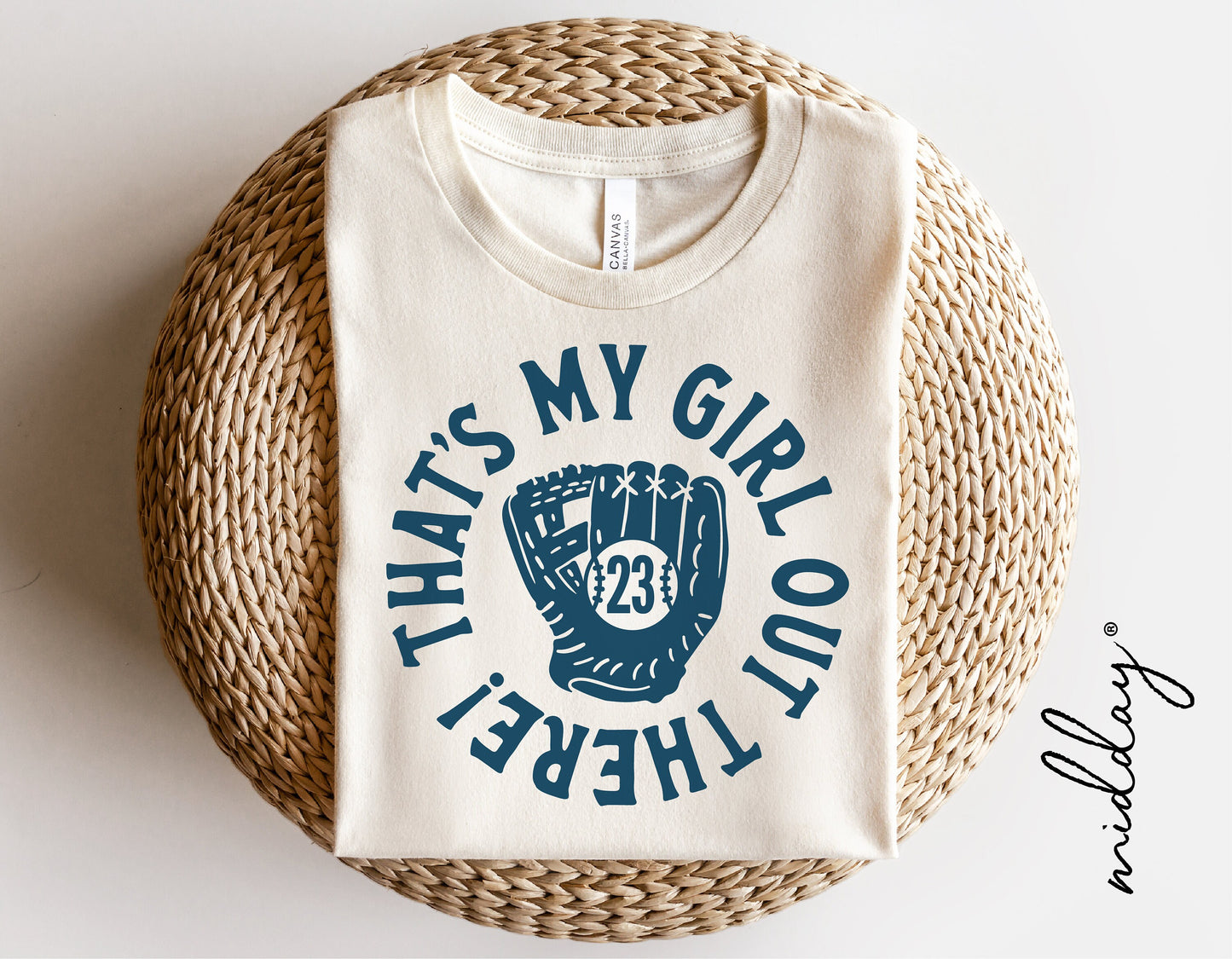 White t-shirt with 'That's My Girl Out There!' graphic and softball glove design on wicker basket; perfect for softball moms.