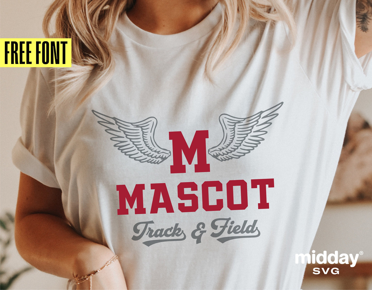 Woman wearing a white t-shirt with 'M Mascot Track & Field' design featuring winged letters in red and gray font.