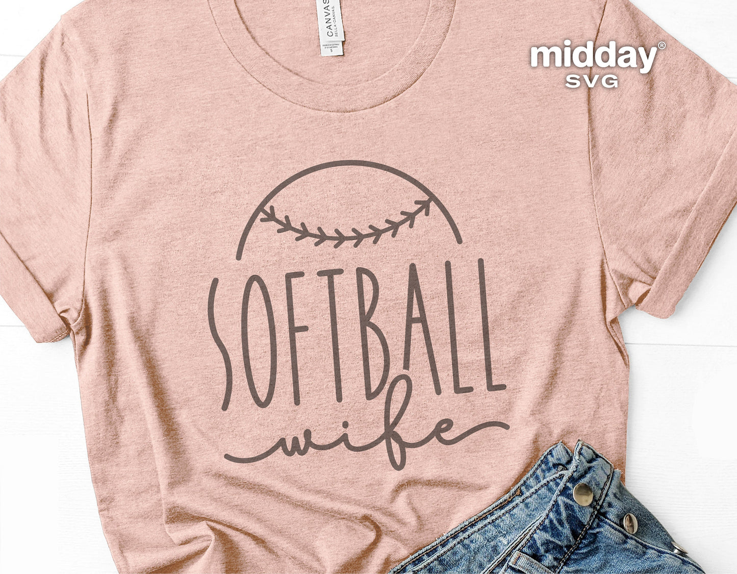 T-shirt with 'Softball Wife' design in black lettering, featuring a softball illustration, laid next to blue jeans on a white surface.