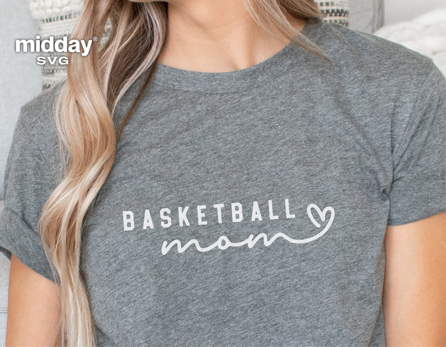 Close-up of a grey t-shirt featuring a white 'Basketball Mom' design with a heart, worn by a person with long blonde hair.