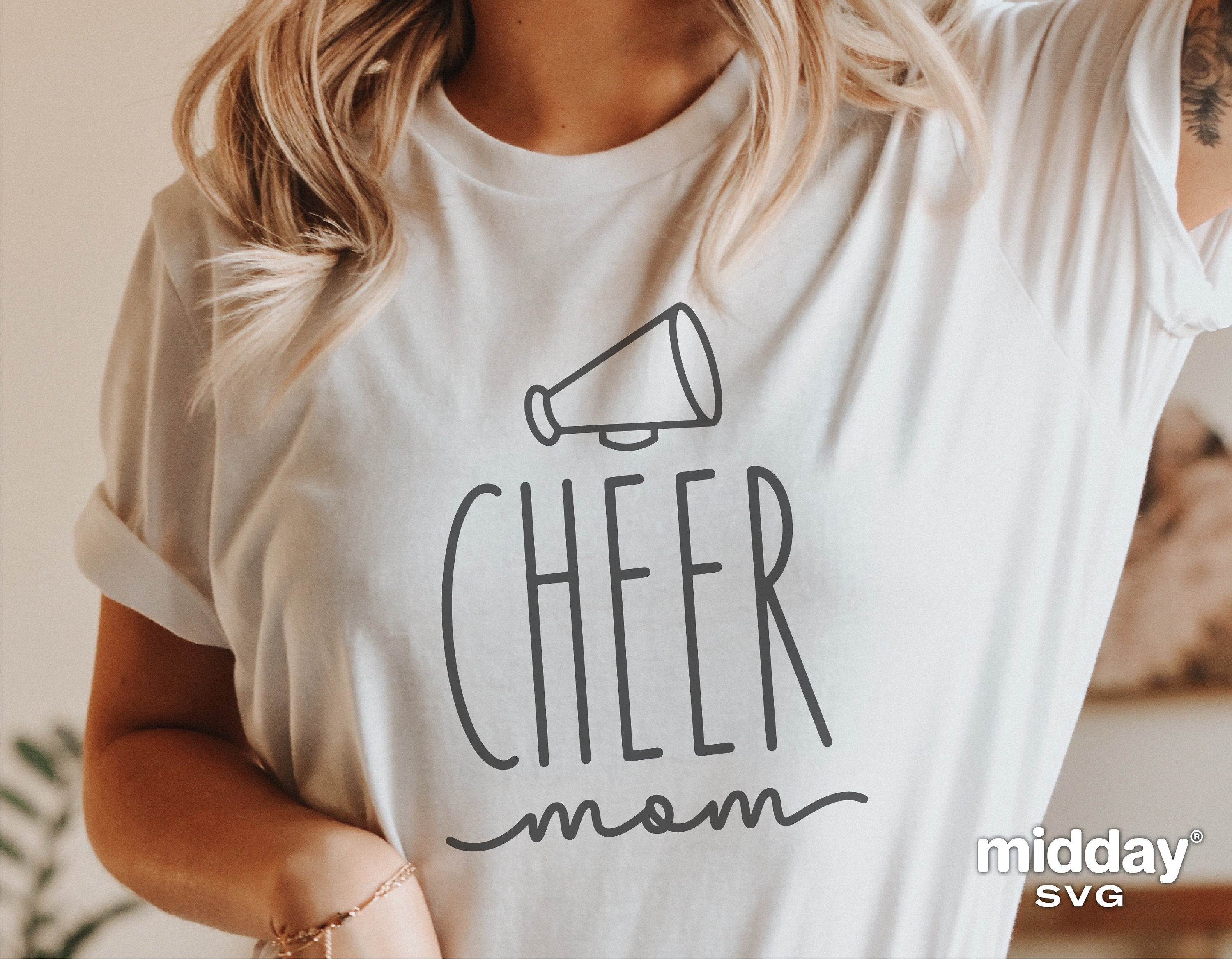 Woman wearing a white Cheer Mom shirt with megaphone graphic, perfect for cheerleading enthusiasts and sublimation projects.