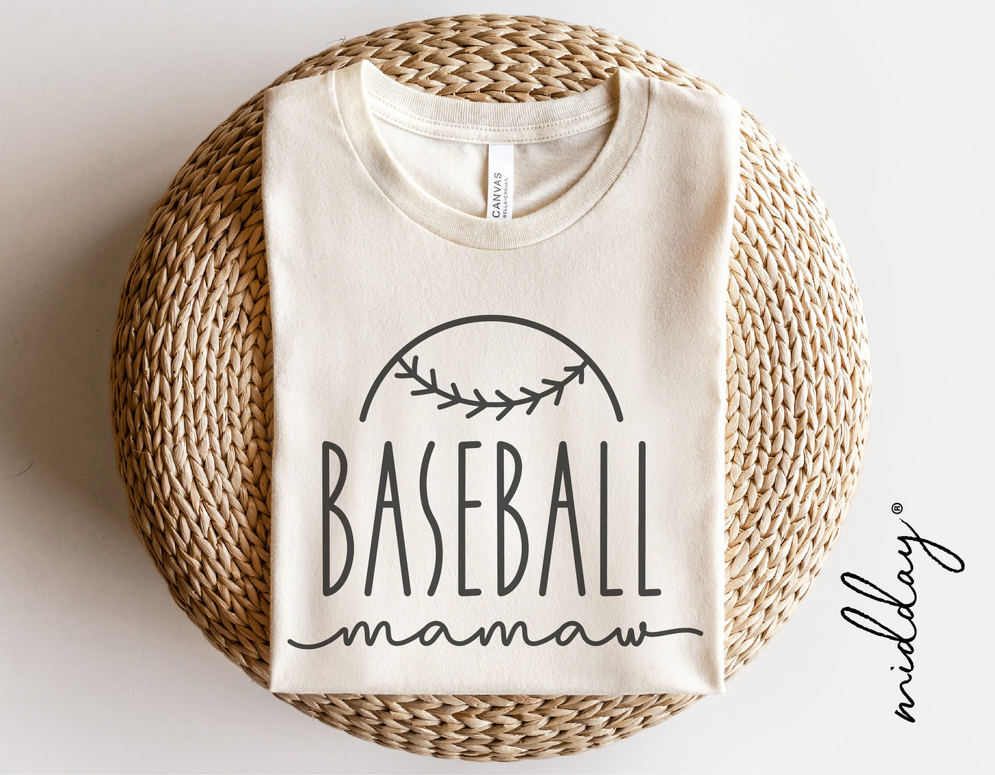 Cream Baseball Mamaw shirt displayed on a woven mat, featuring a baseball graphic and cursive text, perfect for baseball moms.