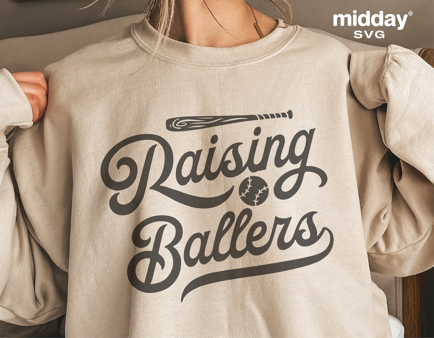Sweatshirt with 'Raising Ballers' SVG design, perfect for baseball moms or dads. Ideal for Cricut and Silhouette crafting projects.
