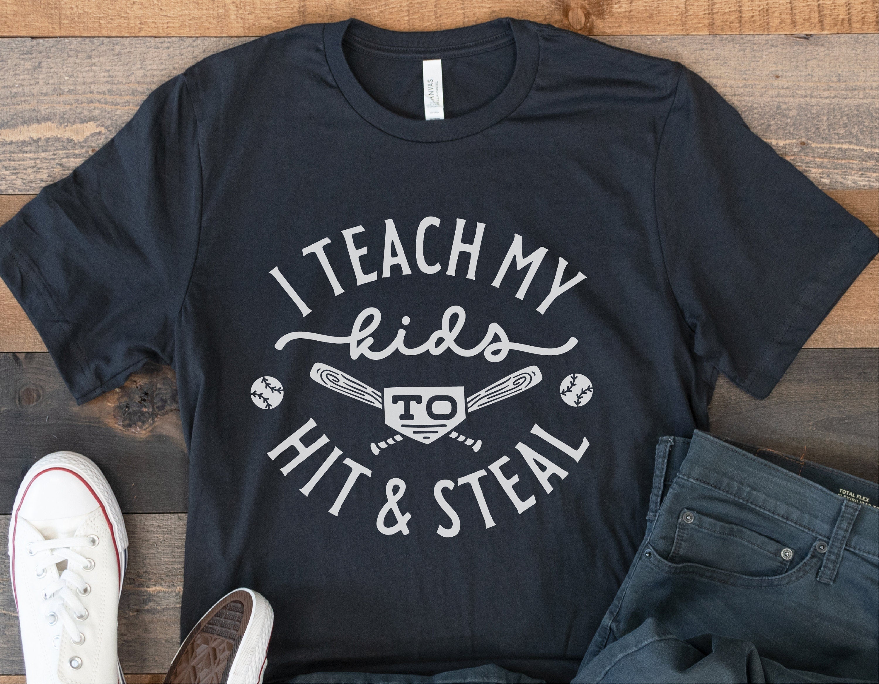 Funny baseball shirt with 'I Teach My Kids to Hit & Steal' design, ideal for baseball moms, featuring bats and balls graphics.