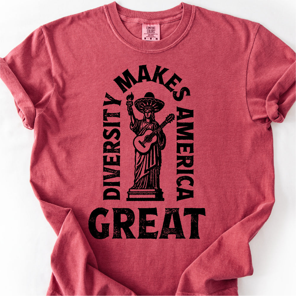 A red t-shirt with a graphic design featuring a statue of a woman holding a guitar and the text "DIVERSITY MAKES AMERICA GREAT" printed on it.