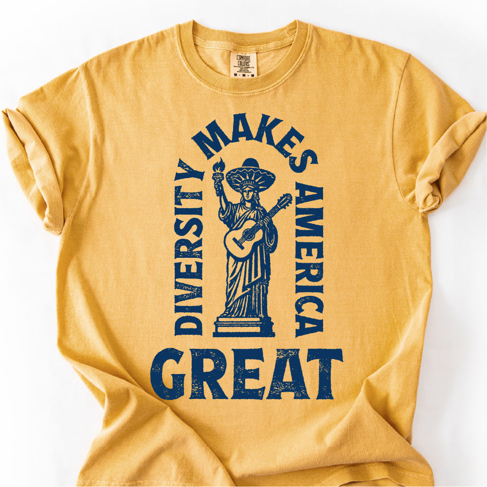 A yellow t-shirt with a graphic design featuring a statue of a woman holding a guitar and the text "DIVERSITY MAKES AMERICA GREAT" printed on it.