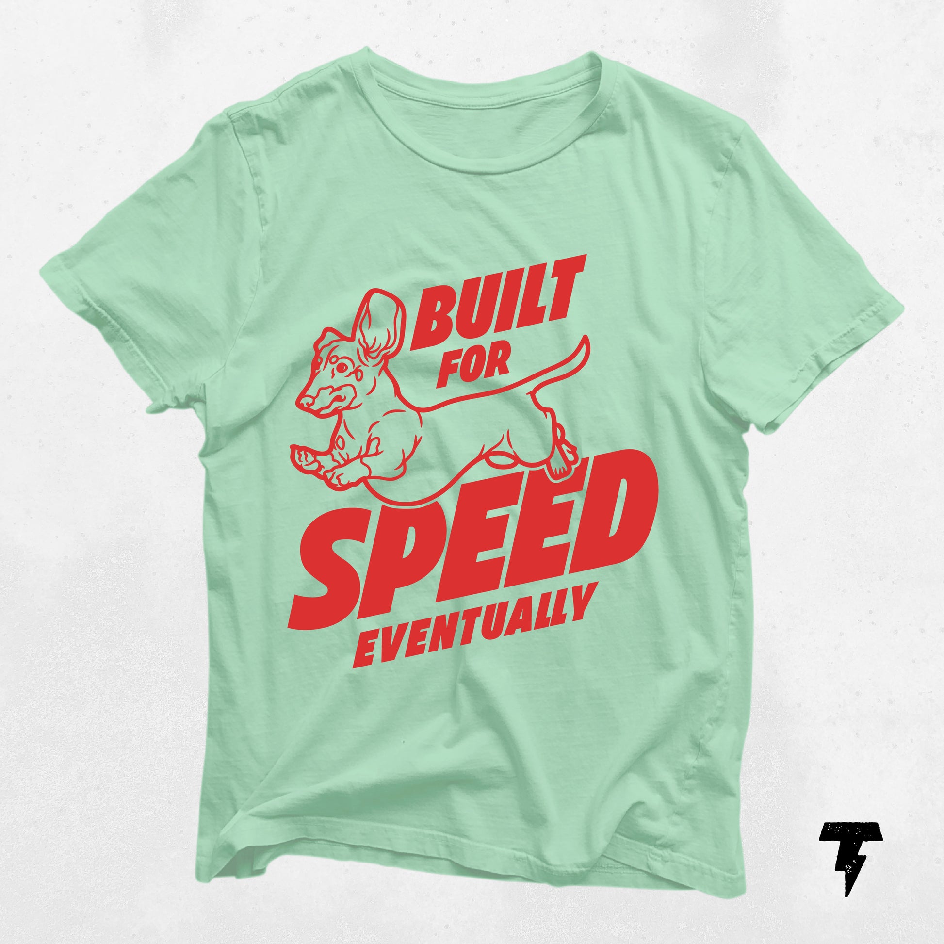 Mint green dachshund shirt with red text 'Built for Speed Eventually' and cartoon wiener dog graphic.