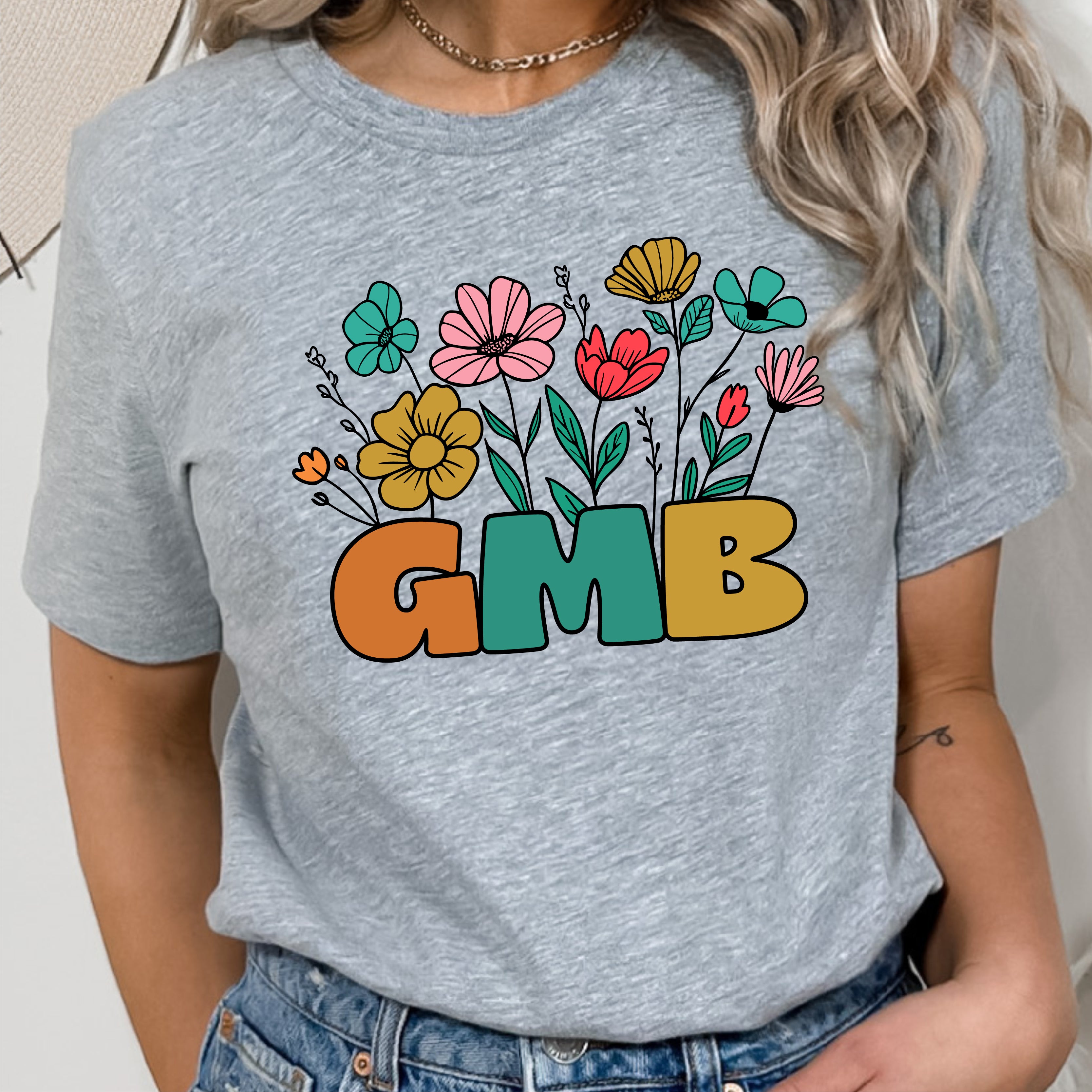 a woman wearing a gray t - shirt with colorful flowers and the word gmb