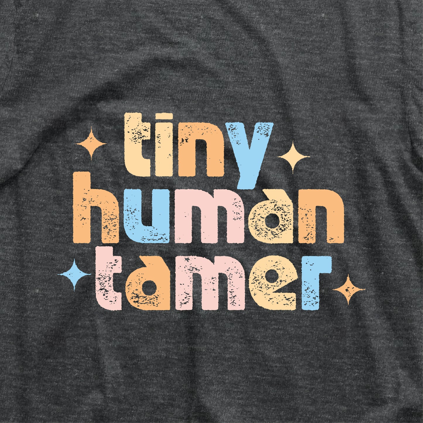 "Tiny Human Tamer" shirt in colorful font on dark fabric, ideal for pre-k and kindergarten teachers. Lightweight, breathable cotton.