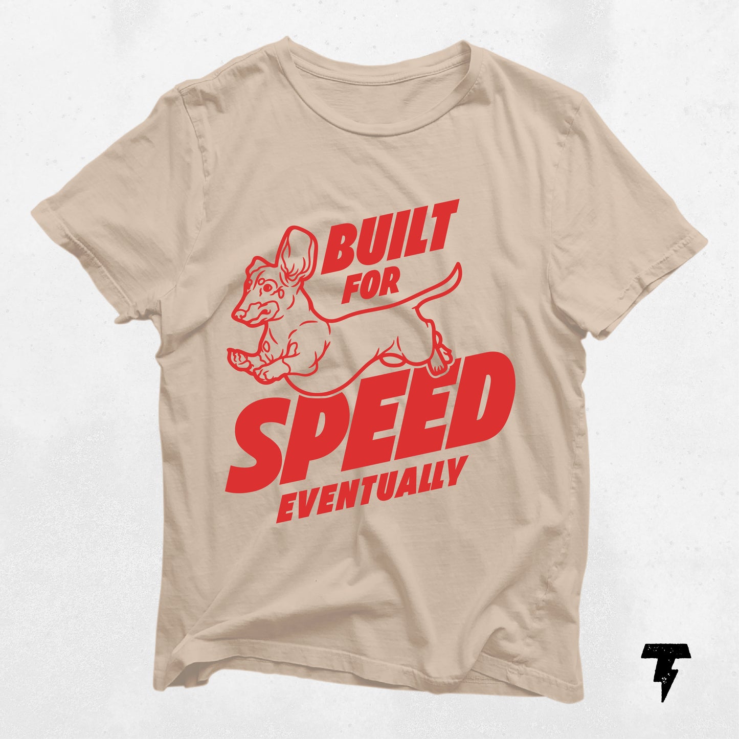 Beige Dachshund shirt with 'Built For Speed Eventually' red graphic and cartoon Doxie design for dog lovers.